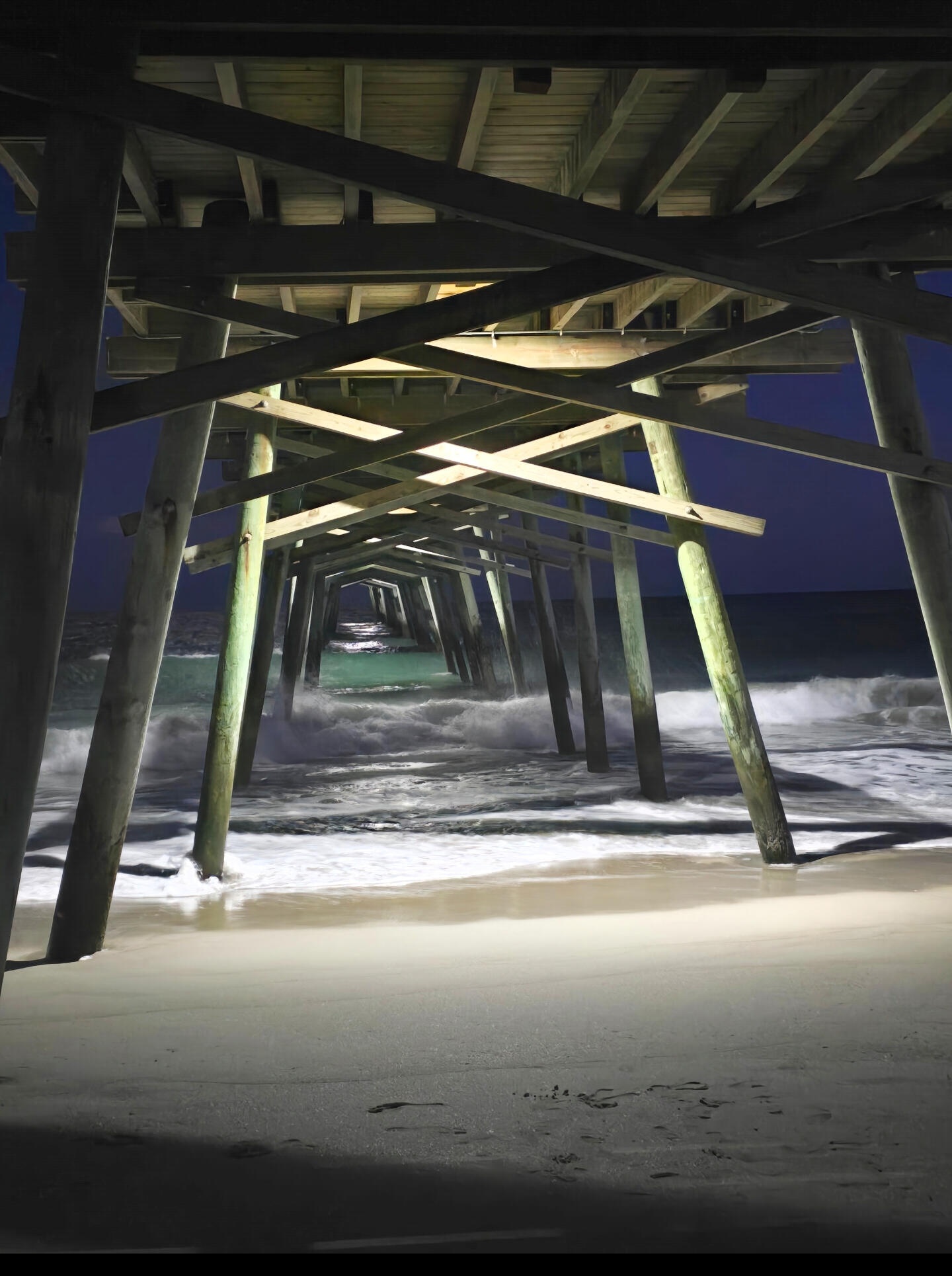 About Smooth Static Radio Night view beneath the Emerald Isle Fishing Pier with waves rolling in along the beach.